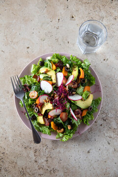 Over the top view of a pixbae fruit salad with lettuce, avocado, olives, pistachio, radicches.