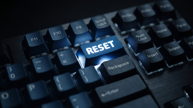 Glowing blue reset button on a black computer keyboard, illuminated reset key for system recovery, concept of starting over and digital troubleshooting