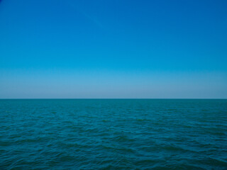 Fototapeta premium Deep Blue Ocean Horizon Under Clear Sky: Vast turquoise open sea surface and calm waves with ample copy space ideal background maritime sustainability and corporate concept.