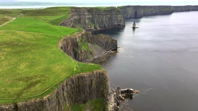 A drone shot of the Cliffs of Moher at cloudy weather, the tallest sea cliffs of the rugged West Clare Coast of Ireland.