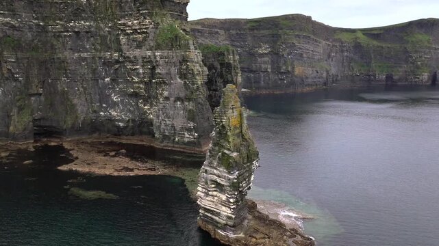 A drone shot of the Cliffs of Moher at cloudy weather, the tallest sea cliffs of the rugged West Clare Coast of Ireland.