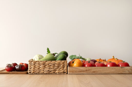 Minimal aesthetic composition with various vegetables in boxes on table, empty neutral wall background, soft natural light