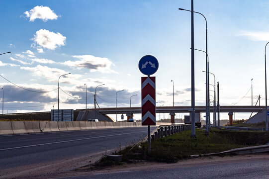 Modern highway intersection featuring clear directional road signs and concrete safety barriers under a vast blue sky