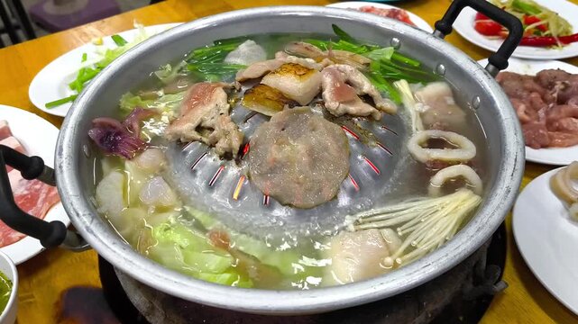 Traditional Thai BBQ pork hot pot known as Moo Kratha grilling meat and vegetables