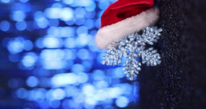 Santa hat with snowflakes on a dark surface with blue bokeh background, Christmas theme. 
