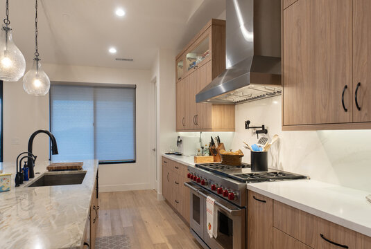 Modern kitchen with wood veneer cabinets marble countertop stainless range hood lighting room style