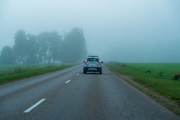 Police patrol car driving along a rural road in dense morning fog © Edijs