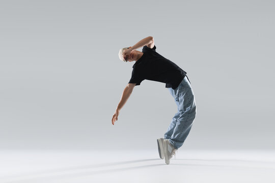 Young man dancing hip-hop on light background, space for text