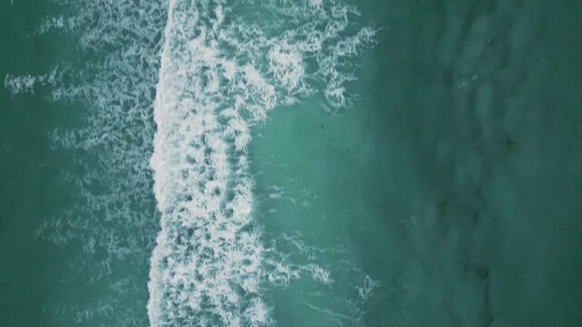 Aerial view of frothy waves rippling across teal ocean water