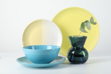 Set of stylish tableware and floral decor on white background
