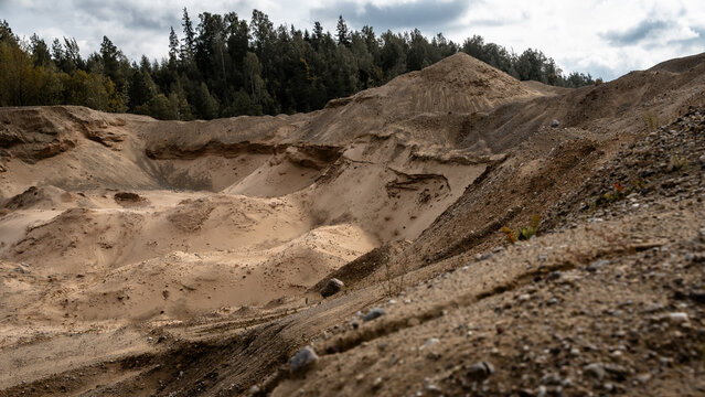 Sand and gravel quarry with exposed sediment layers and aggregate piles