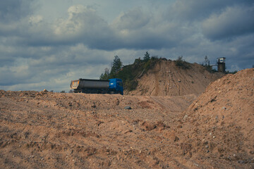 Dump truck driving through an open pit sand and gravel quarry © Edijs