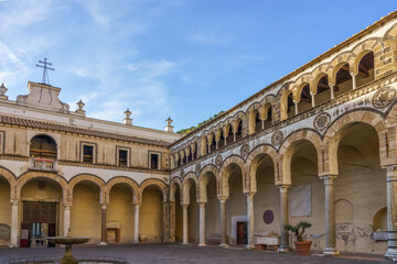 Obraz premium Ancient Romanesque courtyard portico of Salerno Cathedral in Italy. Scenic view of the medieval atrium at Duomo di San Matteo in Salerno with historic stone arches and antique marble columns.