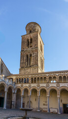 Fototapeta premium Ancient Romanesque bell tower of Salerno Cathedral in Italy. Scenic view of the historic medieval campanile bell tower rising above the atrium courtyard arches at Duomo di San Matteo in Salerno