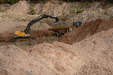 Excavator loading an articulated dump truck in a sand and gravel quarry © Edijs