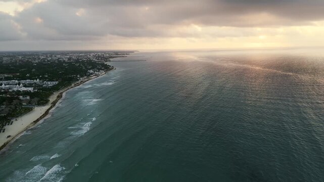 Aerial view of a coastline curving beneath golden dusk light