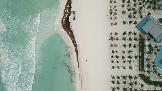 Aerial view of a resort coastline with turquoise waves and drifting sargassum