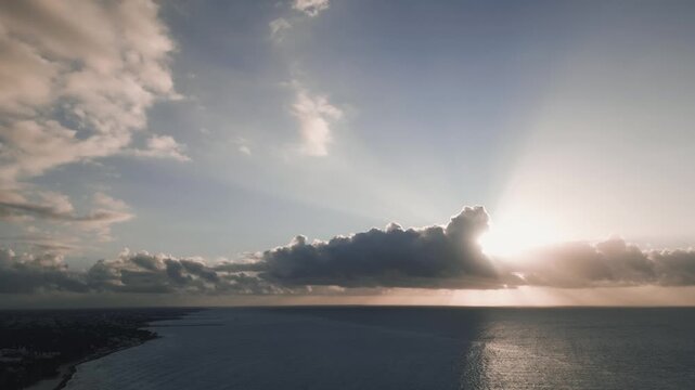 Radiant sunburst breaking through clouds over a calm sea horizon