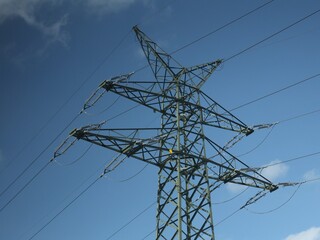 Vue en perspective d'un pylône électrique en ossature métallique, portant des lignes à haute tension. Structure dédiée au transport de l'énergie par voie aérienne. Ciel bleu en arrière plan. © Xavier