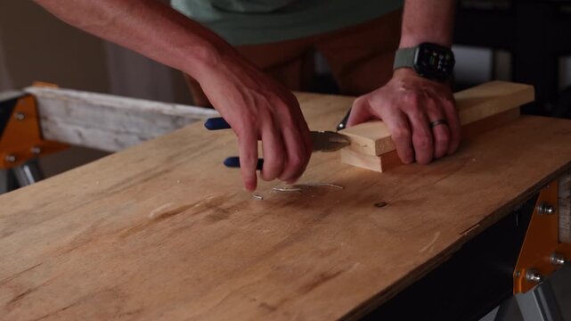 Man pulls finishing nails out of piece of wood with lineman pliers