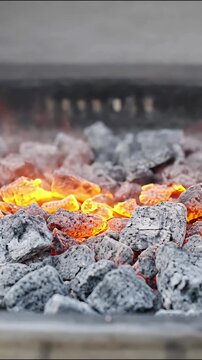 Glowing charcoal embers burning bright with smoke for barbecue cooking