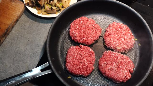 Stockholm, Sweden A cook in a residential kitchen fries homemade hamburger patties in a frying pan. 