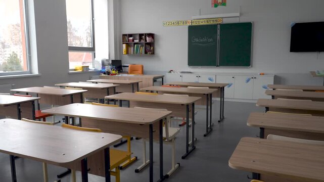 Empty School Classroom With Wooden Desks And Green Blackboard
