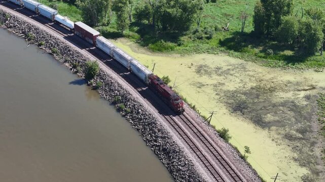 freight train being pulled along the back waters of the Mississippi river in summer landscape