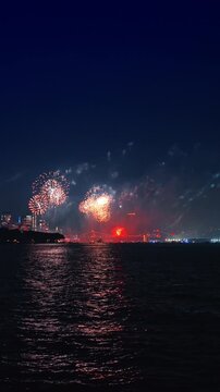 Festive fireworks splashing in the dark night sky. New York City celebration of the Fourth July. Vertical video.
