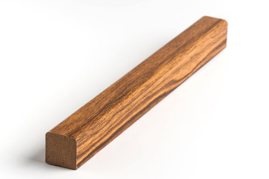 Studio photograph of a rectangular molding profile with a warm wood-effect finish and visible grain texture