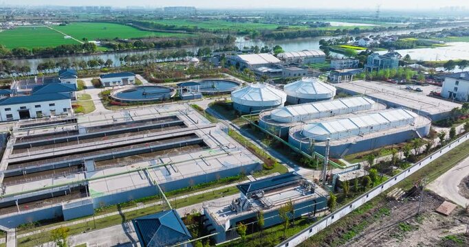 High angle aerial view of a modern water treatment plant facility featuring circular pools and rectangular basins under clear daylight.