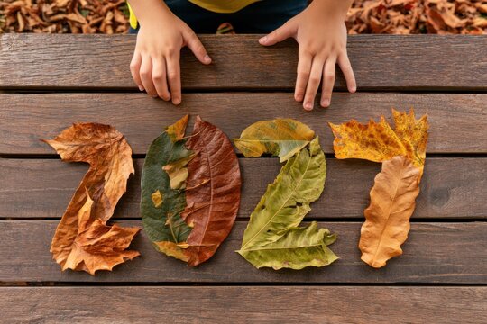 The year 2027 made out of dry leafes by boy hands