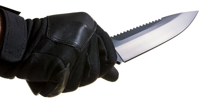 Isolated hand in black tactical glove holding a sharp, serrated combat knife with steel blade.