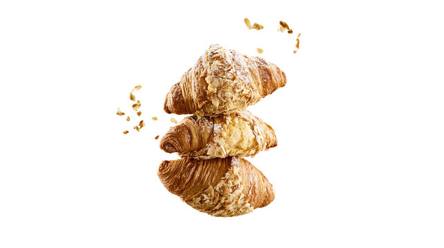 Isolated delicious freshly baked stacked almond croissants with powdered sugar and flying flakes