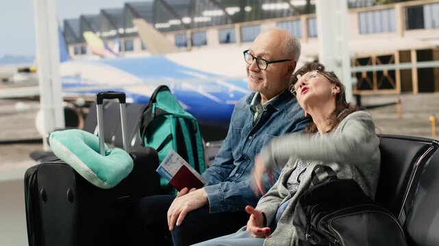 Joyful retirees in airport lounge waiting area smiling and talking, preparing for boarding airplane, highlighting optimistic and adventurous retirement.