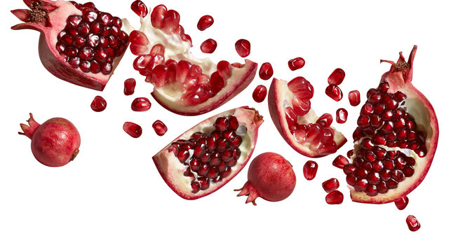 Isolated fresh pomegranate fruit with scattered red arils, whole, and various cut pieces
