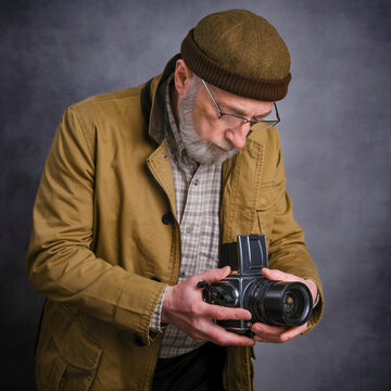 portrait of a senior male photographer shooting pictures with a classic, medium format, film camera