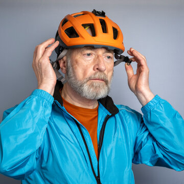 portrait of senior male cyclist putting a bike helmet on