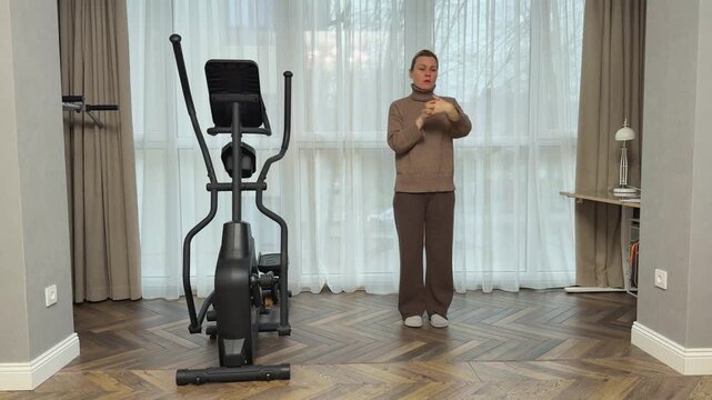 Woman in warm home clothes lifts arms up with inhale and lowers them down on exhale. Calm breathing exercise combined with stretching.