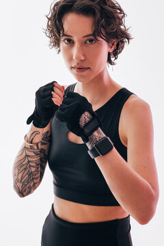 Portrait of a slim woman in a fighting stance looking at the camera, wearing gloves