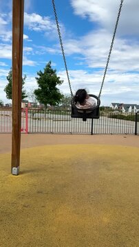 Toddler Girl Swinging on Playground Swing at Whitehouse, Milton Keynes, UK