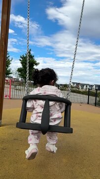 Toddler Girl Swinging on Playground Swing in Slow Motion