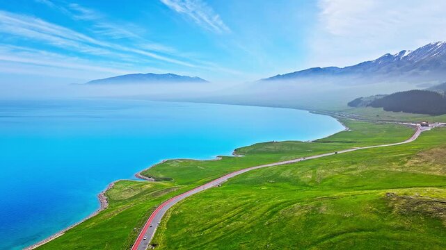 Aerial drone view of scenic asphalt road along turquoise waters of Sayram Lake, Xinjiang, China