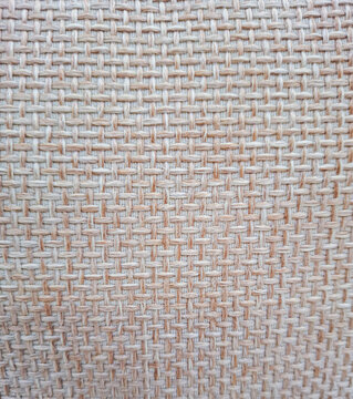 Close view of coarse light beige woven fabric showcasing a square cross hatch pattern in a textile setting