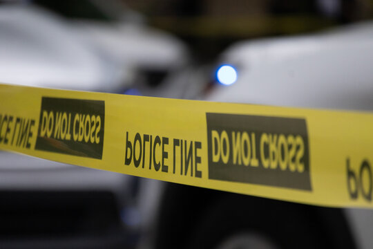 Police tape with emergency lights in background