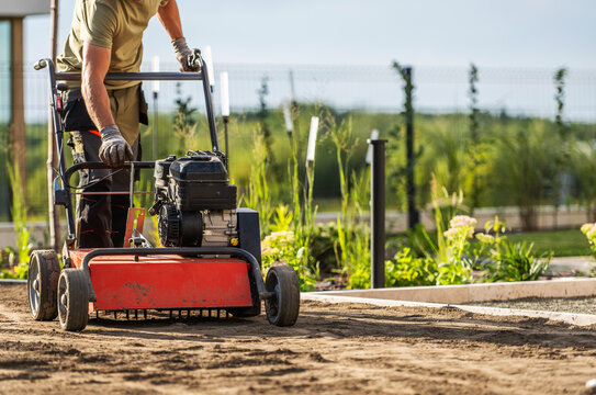 Gardener handling a lawn scarifier on bare soil