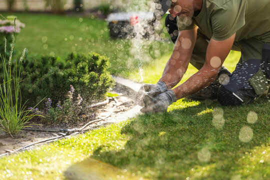 Gloved gardener adjusting a lawn sprinkler