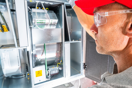 Technician inspecting an open ventilation unit