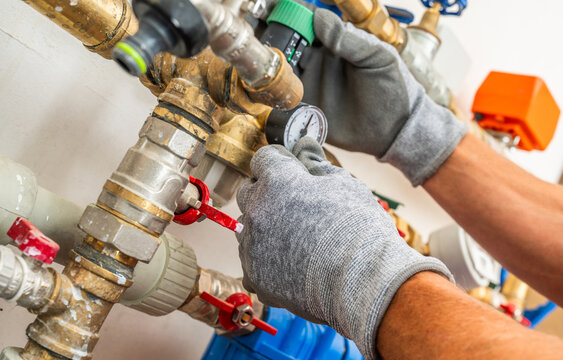 Plumber adjusting a water pressure regulator