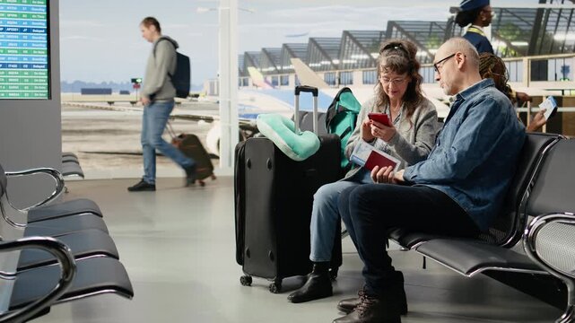 Senior couple checking travel itinerary on smartphone at airport